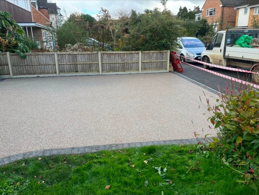 Finished resin bound driveway with block paving border and timber panel fencing.