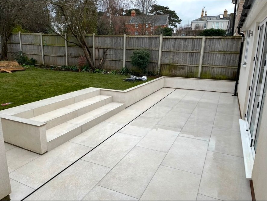 Contemporary ivory porcelain terrace with matching steps, retaining wall and slot drain.