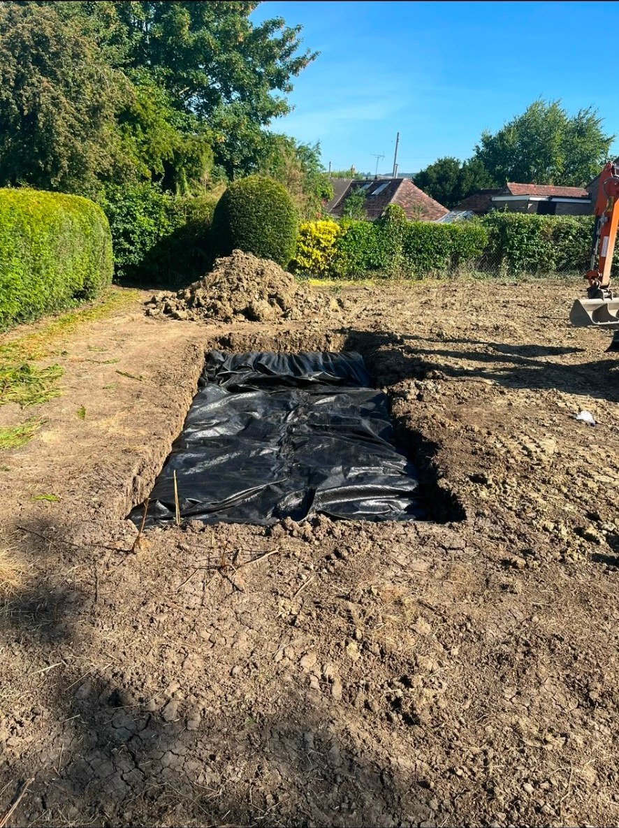 Garden excavation showing groundworks, weed membrane liner and digger bucket