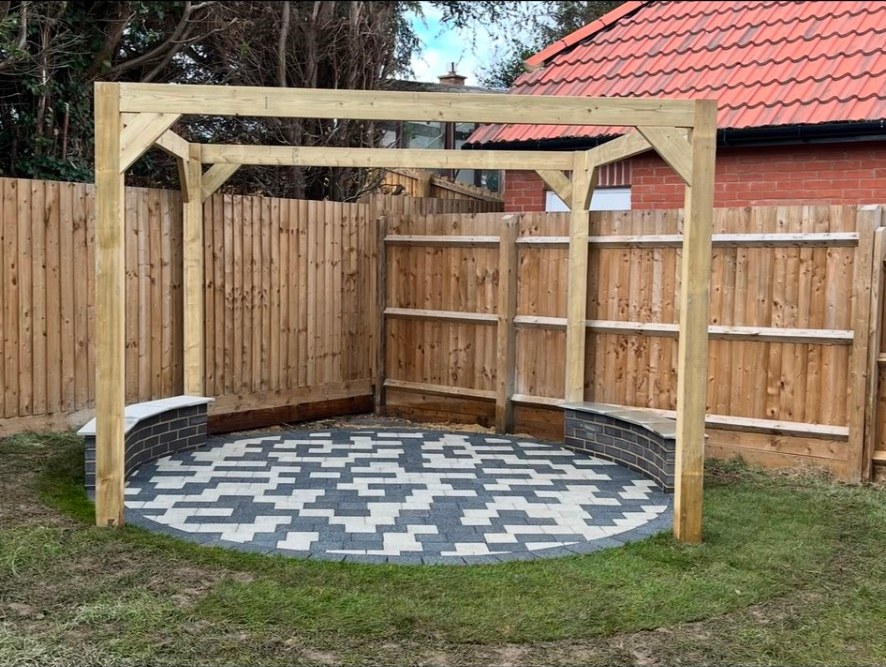 Circular block paving patio with timber pergola, brick seating, and new garden fencing.